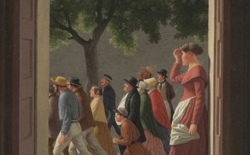 View through an open doorway. A woman stands in the door looking left. Outside a crowd of people are running towards the left.